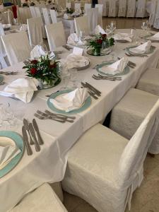 um grupo de mesas com panos de mesa brancos e guardanapos em Hotel Casa Del Gourmet em Siderno Marina