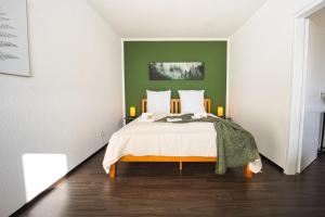 HejU - Luxury Aussicht - Kingsize Bed - Kitchen - Bathtub في لوبيك: غرفة نوم بسرير مع جدار أخضر