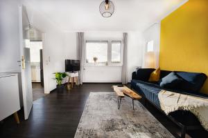 ein Wohnzimmer mit einem schwarzen Sofa und einer gelben Wand in der Unterkunft HejU - Luxury Aussicht - Kingsize Bed - Kitchen - Bathtub in Lübeck