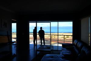 two people standing in a living room looking out at the ocean at Atlantic Dunes Unit 11, Self Catering in Rand Rifles