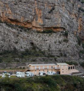 a building with vehicles parked in front of a mountain at Auto kamp Titograd in Podgorica