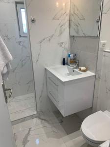 uma casa de banho branca com um lavatório e um chuveiro em Le 53 Bellevue em Cogolin