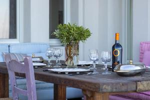 a wooden table with glasses and a bottle of wine at Villa Salty in Azolimnos Syros