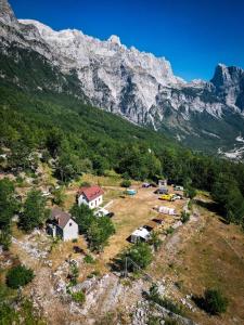 un gruppo di case su un campo con una montagna di Guesthouse Freskia a Theth