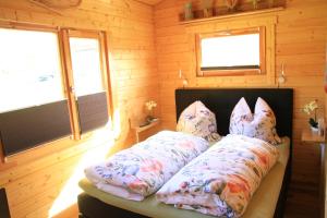 a bed in a wooden room with pillows on it at Ferienhäuser Seeblick in Langenhagen