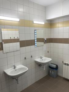 a bathroom with two sinks and a trash can at Hostel przy Stadionie in Jaworzno