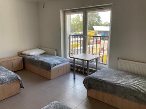 a room with two beds and a table and a window at Hostel przy Stadionie in Jaworzno