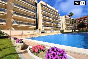 a large apartment building with a swimming pool and flowers at Ventu-Park in Salou