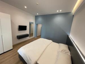 a bedroom with a white bed and a television at Ladi Rooms in Tirana