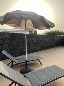 a chair and an umbrella on a patio at BUNGALOW APARTAMENTO SOL in Famara