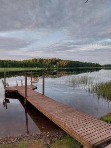 a wooden dock with two benches on a lake at Arolahti Suite ( Rapojärvi ) in Kouvola