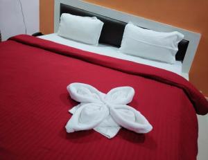 een bed met een rode deken met een bloem erop bij Hotel Firdous Palace, Surajpur Chhattisgarh 