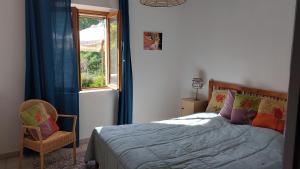 1 dormitorio con cama, ventana y silla en Freundliches Haus mit Pool und großem Garten en Buis-les-Baronnies