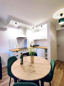 une cuisine avec une table en bois et des chaises vertes dans l'établissement Szmaragdowy Apartament nad Zalewem, à Serock