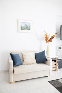 a white living room with a couch with blue pillows at Seaside Penthouse in Kalamata in Kalamata