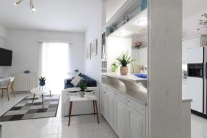 a kitchen with white cabinets and a living room at Seaside Penthouse in Kalamata in Kalamata