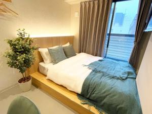 a bedroom with a bed with a plant and a window at R Hotel Namba in Osaka