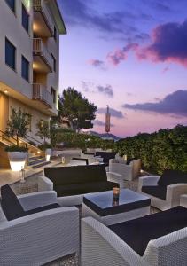a patio with couches and a clock tower in the background at Hotel La Baia in Diano Marina