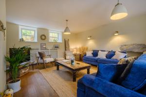 a living room with blue couches and a coffee table at Woodside Cottage - Cartmel Fell, Windermere in Windermere