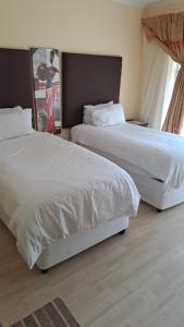 two beds in a hotel room with white sheets at Phokela Guest House in Mokopane