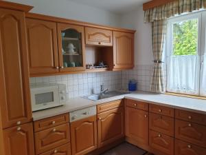 cocina con armarios de madera, fregadero y microondas en Ferienwohnung Claudia, en Salzburgo