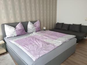 een groot bed met paarse en witte lakens en kussens bij Ferienwohnung Claudia in Salzburg