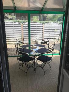 een tafel en stoelen op een afgeschermde veranda bij Villa refaite à neuf à 200 mètres de la plage in Soulac-sur-Mer