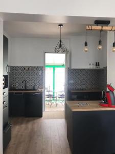 een keuken met zwarte werkbladen en een tafel en een raam bij Villa refaite à neuf à 200 mètres de la plage in Soulac-sur-Mer