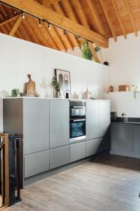 a kitchen with white cabinets and a wooden ceiling at The Honeybee's Nest - Semi-rural Barn Conversion close to Leavesden Studios in Leverstock Green
