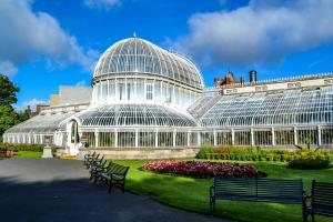 uma grande casa de vidro com bancos num jardim em The Arches New Modern 2BR em Belfast