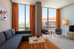 a living room with a couch and large windows at Adagio Doha in Doha