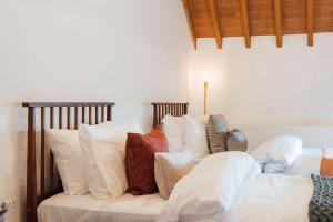 a bed with white pillows on top of it at The Honeybee's Nest - Semi-rural Barn Conversion close to Leavesden Studios in Leverstock Green