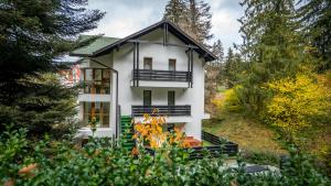 a white house with a balcony in a forest at Family TreeZ Premium Apartments in Poiana Brasov