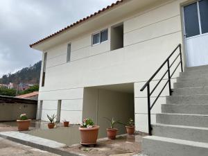 ein weißes Haus mit Topfpflanzen davor in der Unterkunft Agradable departamento con estacionamiento gratis in Sucre
