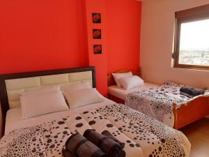 2 camas en una habitación con paredes de color naranja en Geni Apartment, en Korçë