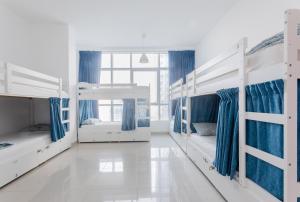 Habitación con 3 literas y cortinas azules. en Skyview Host en Dubái