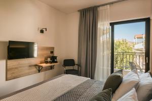 a bedroom with a bed and a tv and a balcony at Skala Hotel in Skala Kefalonias