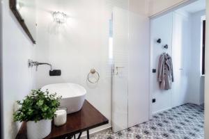 a bathroom with a white tub and a sink at Cesare 22 - The House Of Travelers in Como