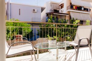 a balcony with a glass table and chairs at CACTUS - Blooming Garden Apartments in Kalamata