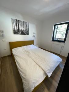 1 dormitorio con 1 cama blanca y ventana en Sunshine Apartments Golte E4, en Mozirska Koča