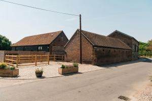 dois edifícios de tijolos com vasos de plantas na berma da estrada em The Honeybee's Nest - Semi-rural Barn Conversion close to Leavesden Studios em Leverstock Green