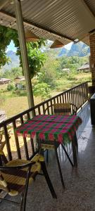 a table and chairs on a porch with a view of mountains at Du Già Vân Chung Homestay in Làng Cac