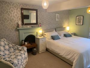 1 dormitorio con 1 cama con espejo y silla en Talbot House Bed & Breakfast and Tearoom en Pateley Bridge