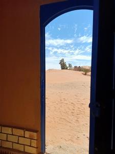 an open door to the desert with a view at Hotel Riad Ali in Merzouga