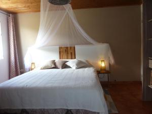 ein Schlafzimmer mit einem weißen Bett mit Baldachin in der Unterkunft Domaine de La Louise in Saint-Joseph