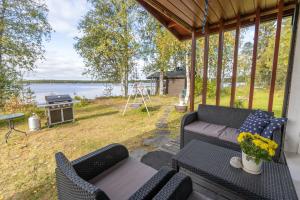 a screened in porch with a couch and a grill at Lapland Sunrise Cottage with lakefront Sauna in Rovaniemi
