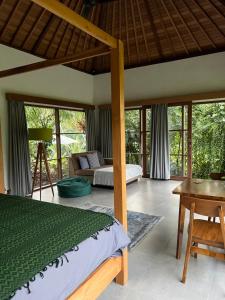 a bedroom with a bed and a desk and some windows at Uma Mupu Retreat in Gianyar