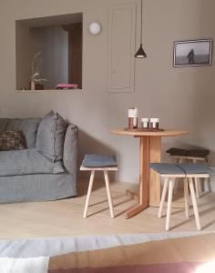 ein Wohnzimmer mit einem Sofa, einem Tisch und 2 Hockern in der Unterkunft La Chambre du 21 in Trouville-sur-Mer