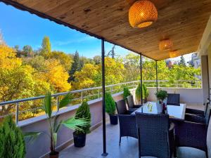 balcón con mesa, sillas y árboles en Парк Апарт-Хотел Виктория 1 en Sandanski