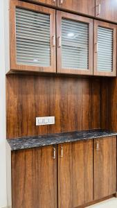 - une cuisine avec des placards en bois et 2 fenêtres dans l'établissement Luxurious 3 BHK Villa In Bhuj - Shivani Homestay, à Bhuj